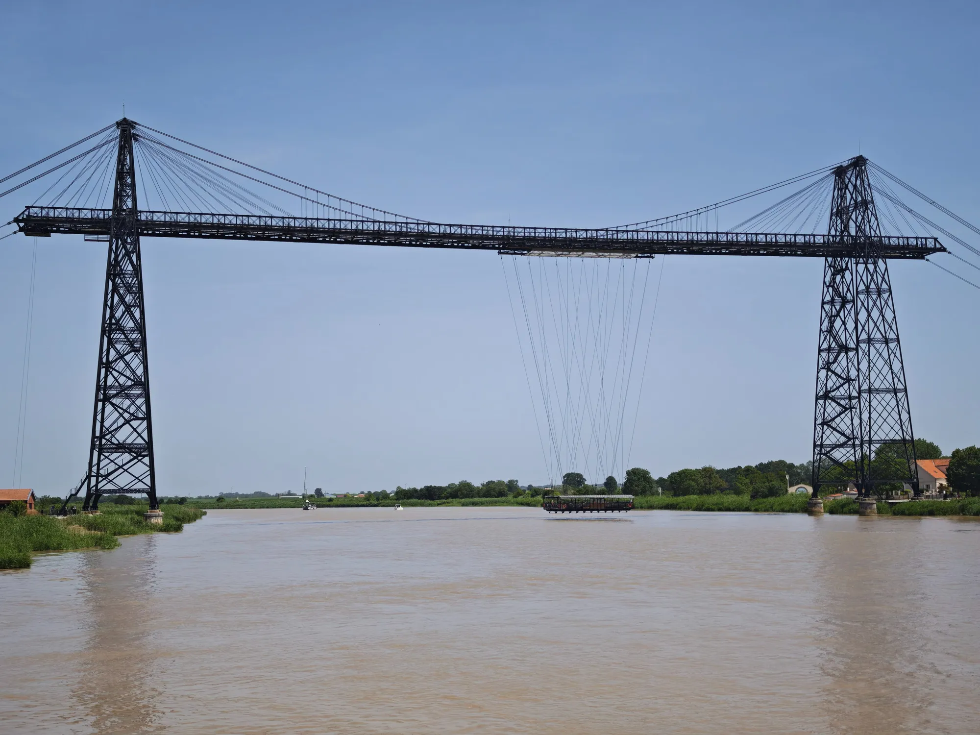 The transporter bridge at Rochefort, its gondola midway across the muddy Charente on cables slung between two tall steel towers.